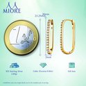 Een euro munt naast gouden rechthoekige oorbellen met zirkonen. Afmetingen en materialen zijn zichtbaar.