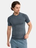 Man in donkergrijs Craft sportshirt met korte mouwen en blauwgrijze sportshort. Gestructureerde stof op schouders en mouwen.
