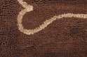 Detail van een bruine shaggy deurmat met een beige gebogen lijn.