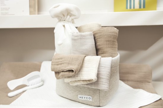 Een mand gevuld met hydrofiele monddoekjes in de kleuren zand, greige en taupe. Naast de mand ligt een borstel.