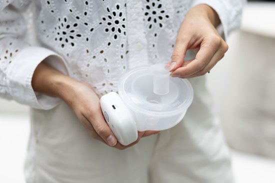 Vrouw houdt witte borstkolf met 26mm borstschildverkleiner vast. De verkleiner is doorzichtig.