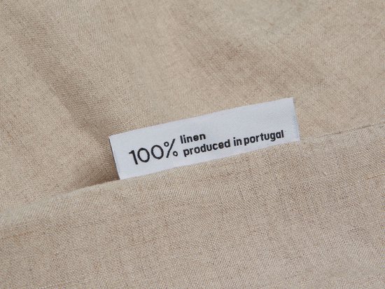Label met tekst 100% linen produced in portugal op een beige linnen stof.