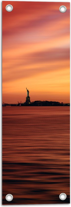 WallClassics - Tuinposter – Vrijheidsbeeld in New York van Ver met Zonsondergang - 20x60 cm Foto op Tuinposter (wanddecoratie voor buiten en binnen)
