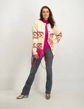 Model met grijze flared jeans, gebreid vest en roze tasje.