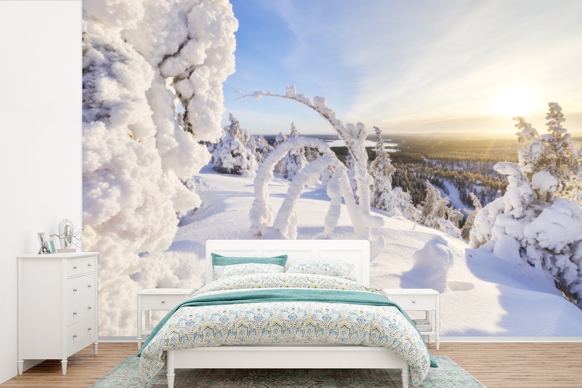 Behang - Fotobehang De zon schijnt op een besneeuwd winterlandschap - Breedte 360 cm x hoogte 240 cm