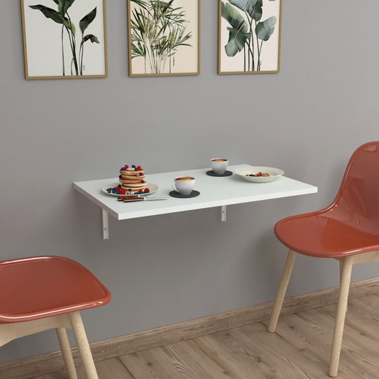 Witte klaptafel met ontbijt, twee oranje stoelen ernaast, aan een grijze muur.
