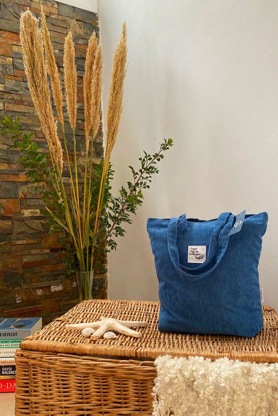 Sac bleu en velours côtelé sur une corbeille décorée.