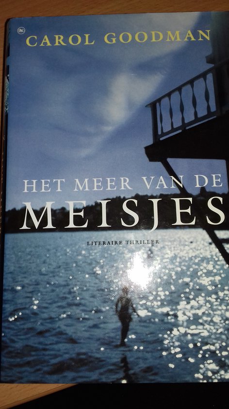 Boekcover met de titel 'Het meer van de meisjes' door Carol Goodman. Een silhouet van een persoon loopt op een spiegelende wateroppervlak.