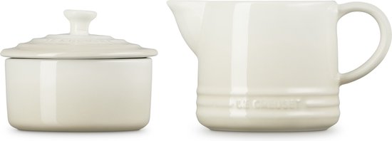 Wit aardewerken suikerpotje met deksel en een melkkannetje, de tekst 'Le Creuset' is zichtbaar op beide.