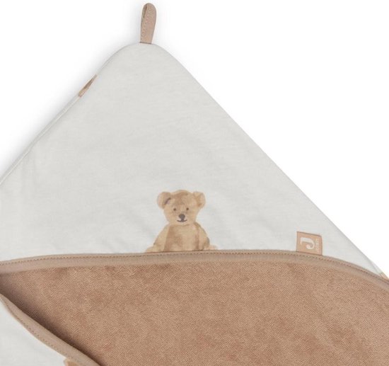Une cape de bain blanche avec un bord beige et un imprimé d'ours brun, pliée.