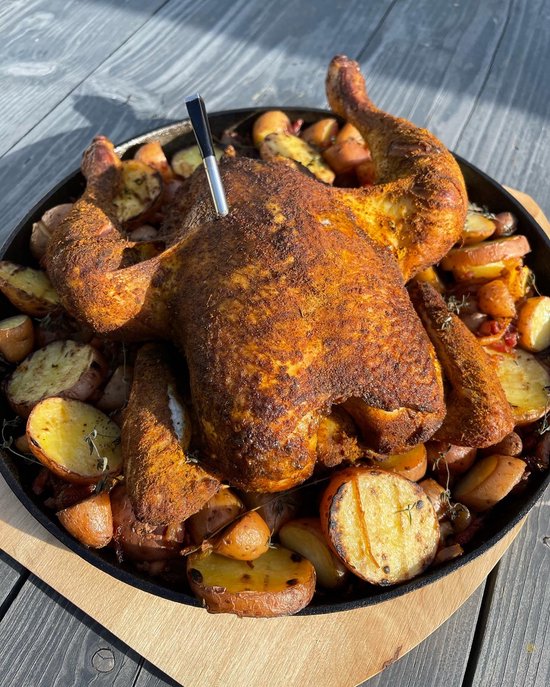 Geroosterde kip met aardappelen en wortelen in een pan.