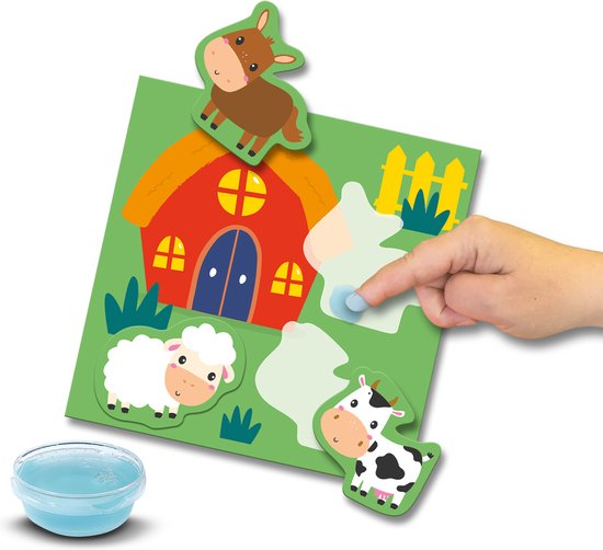 Een kinderhand plakt een bruine paardsticker op een boerderij-achtergrondkaart met een schaap en een koe.
