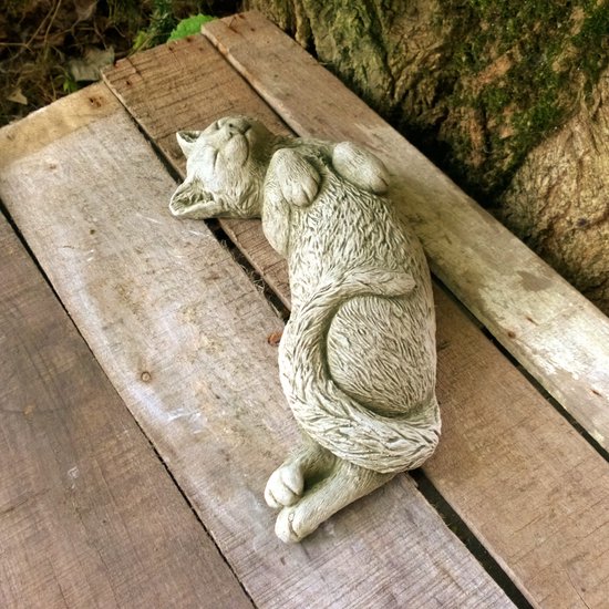 Statue de jardin en béton d'un chat endormi, le dos en l'air et les pattes levées.