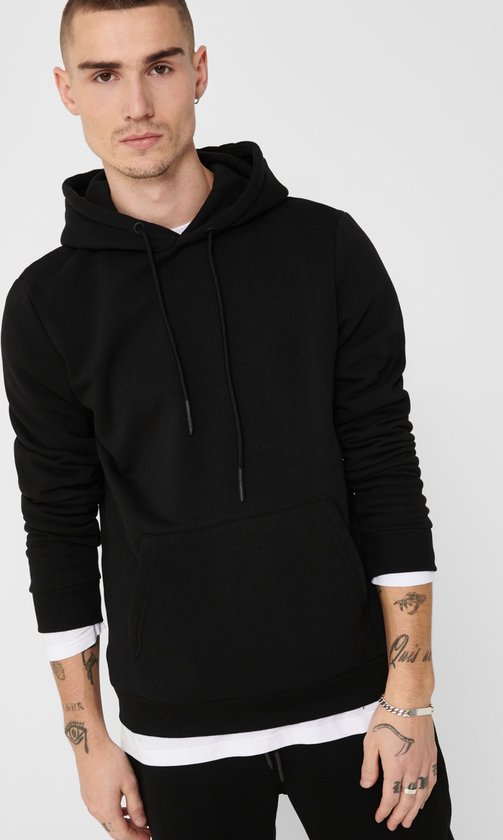 Man met tatoeages draagt een zwarte hoodie met capuchon en kangoeroezak.