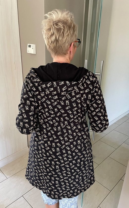 Une femme aux cheveux blonds, vue de dos, portant un peignoir noir à imprimé ours en peluche sur une chemise de nuit bleue.