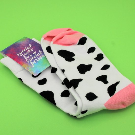 Witte sokken met zwarte koeienvlekken, roze tenen en hielen, met een kaartje met de tekst 'special socks for a special person'.