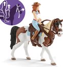 Een meisje met bruine cowboyhoed en blauwe broek rijdt op een bruin-wit gevlekte paard, met een leren zadel.