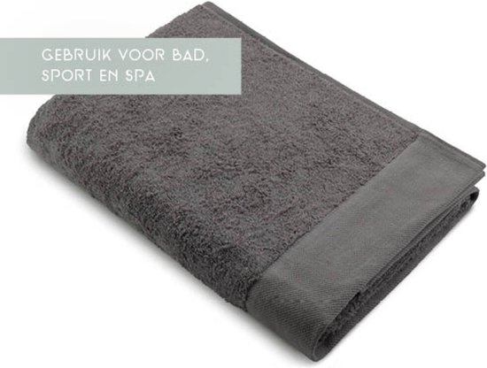 Une serviette grise unie avec un bord tissé et une étiquette. Texte : 'Utilisation pour le bain, le sport et le spa'.