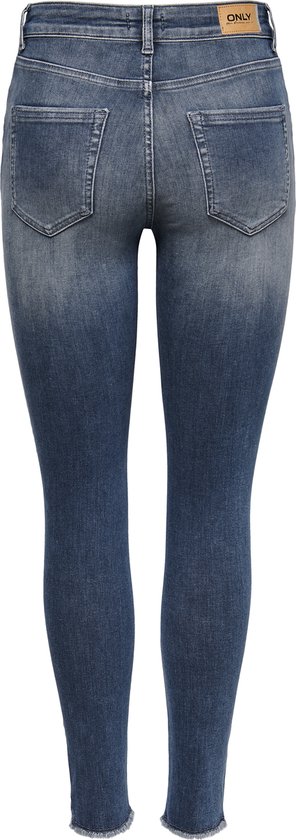 Achterkant van een vrouw in donkerblauwe skinny jeans met rafels aan de onderkant.