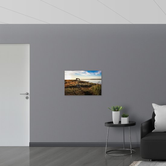 WallClassics - Muursticker - Schommelbank in het Veld aan het Water - 75x50 cm Foto op Muursticker