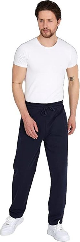 Man in marineblauwe joggingbroek met trekkoord en witte sneakers, staand met witte T-shirt.
