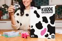 Vrouw met blauwe nagellak en een sweater met koeienprint houdt een kaart van Kuddegedrag vast.