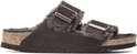 Zijaanzicht van donkerbruine Birkenstock Arizona pantoffels met gespen, lammenvacht voering en kurken zool.