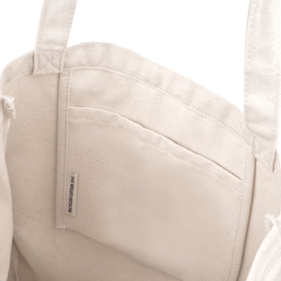 Binnenkant van een crèmekleurige katoenen draagtas met een vak en een label waarop 'RECYCLED COTTON BAG'.