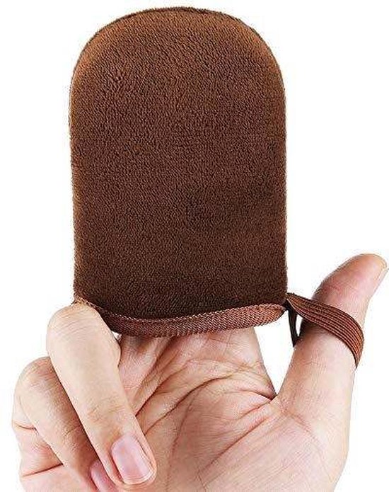 Hand die een bruine zelfbruiner handschoen vasthoudt, met de duim erdoorheen.