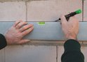 Een man markeert een bakstenen muur met een waterpas en een Pica BIG DRY stift.