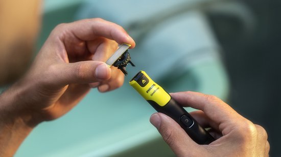 Homme changeant une pièce jointe Philips OneBlade vert clair et argenté sur un appareil noir et vert.