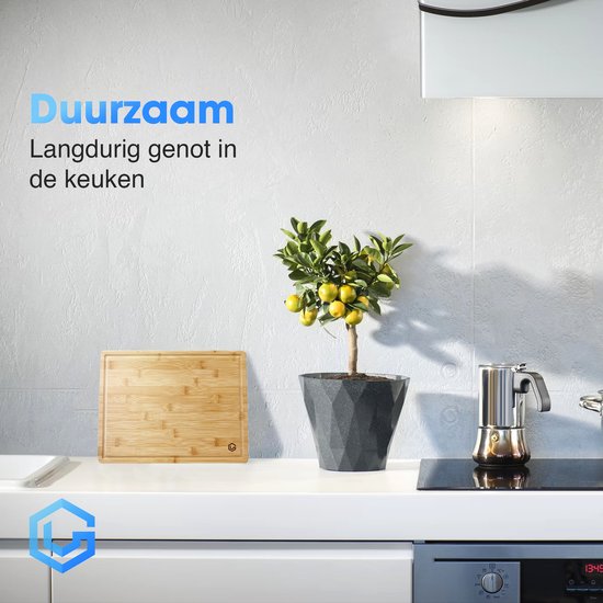 Duurzame bamboe snijplank op een keuken aanrecht met een pot met citroenen en een koffiezetapparaat.