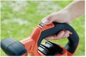 Hand met oranje en zwarte bladblazer, close-up van de ergonomische grip en knoppen.
