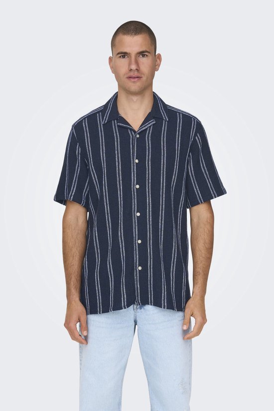 Man in donkerblauw gestreept overhemd en lichtblauwe jeans.