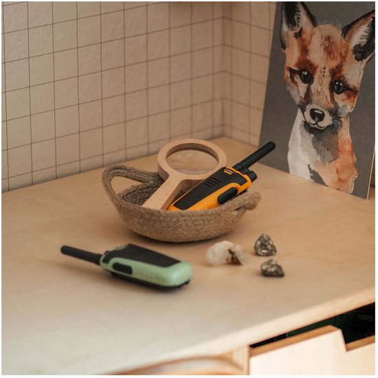 Twee Kidywolf walkietalkies, één groen en één geel, in een mandje van touw. Een vosprent staat op de achtergrond.