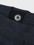 Detail van de tailleband van een donkerblauwe joggingbroek met een knoop.