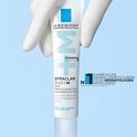 Des gants gris tiennent un tube La Roche-Posay Effaclar Duo+M.
