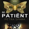 Thriller 'De Patiënt' van Petra Spark met een gouden vlindermasker en een rolstoel in een gang.