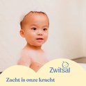 Een schattige baby met zeepbellen in bad, met het Zwitsal logo en tekst 'Zacht is onze kracht'.
