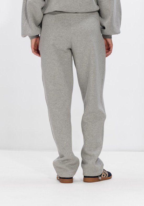 Achterkant van een persoon in een grijze joggingbroek met sneakers.