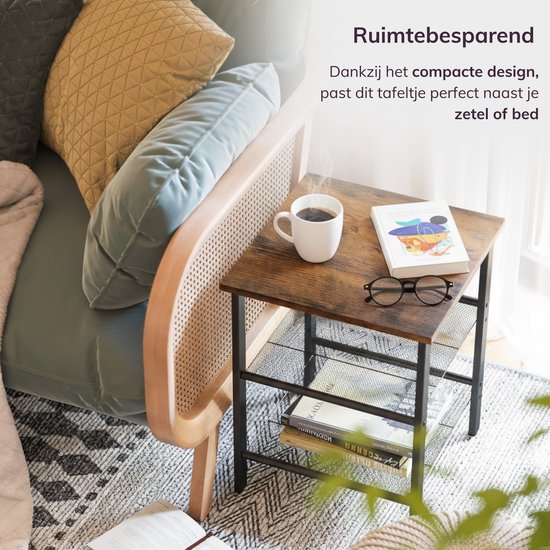 Compacte bijzettafel met bruin tafelblad en zwart frame, naast een bank. Een mok koffie en bril liggen op het tafelblad.