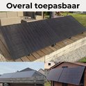 Zwarte zonnepanelen op een houten ondergrond en schuur.