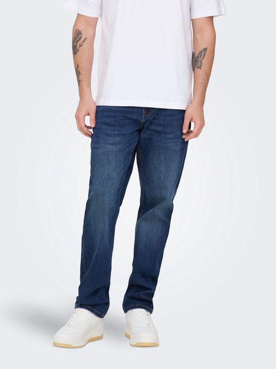 Man in een donkerblauwe spijkerbroek met een witte T-shirt met korte mouwen.
