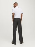 Man van achteren gezien, draagt witte poloshirt met zwarte kraag en biezen, en donkergrijze pantalon.