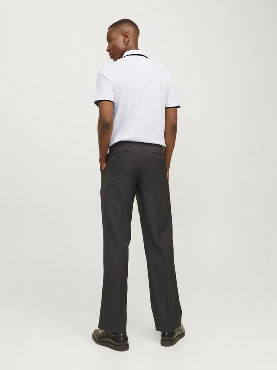 Man van achteren gezien, draagt witte poloshirt met zwarte kraag en biezen, en donkergrijze pantalon.