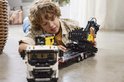 Jongen speelt met LEGO Technic Volvo FMX truck met graafmachine op dieplader.