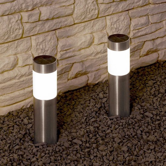 Twee RVS solar tuinlampen met witte lichtkap, staand tussen grijze stenen.