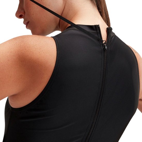Vrouw in zwart Speedo sportbadpak, sluit de rits aan de achterkant.