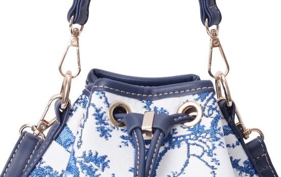 Close-up van sluiting en hengsels van een donkerblauwe emmer tas met wit canvas en blauw Chinoiserie patroon.