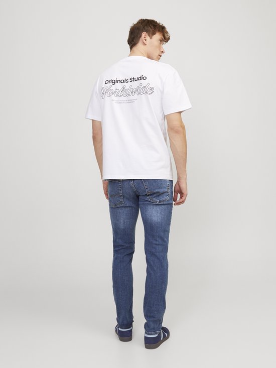 Man met witte t-shirt en een blauwe slim fit jeans, gezien vanaf de achterkant. Het t-shirt heeft tekst op de rug.